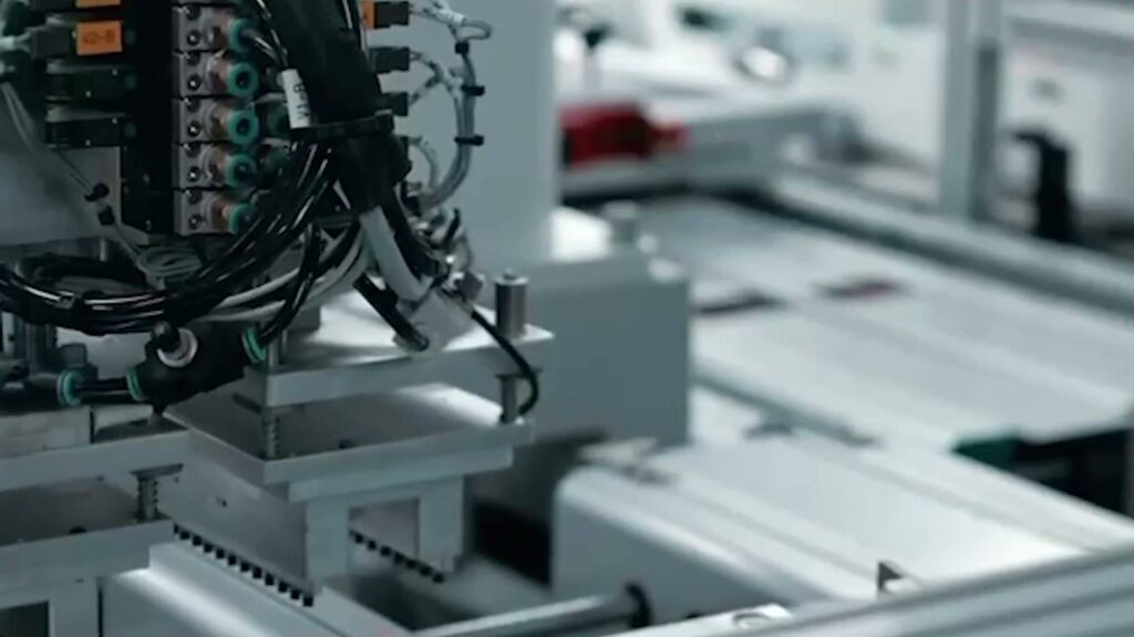 Robotic assembly head positioning an LED luminaire housing on a production line